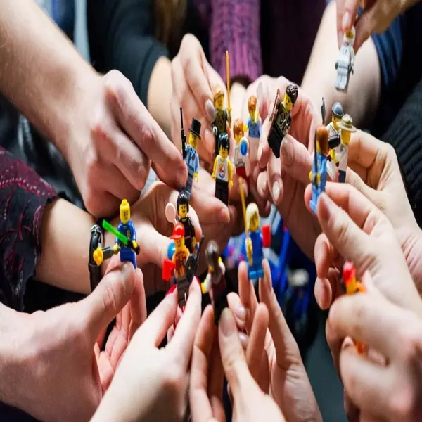 Many hands holding LEGO minifigures